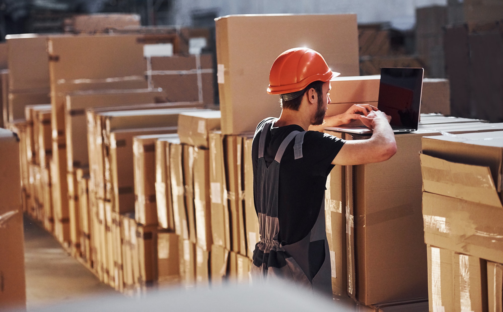 Storage worker in uniform and notepad in hands checks production